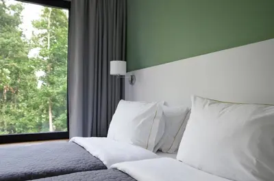 a bedroom with a bed with white pillows and a window at Tip Tap Guest House in Druskininkai