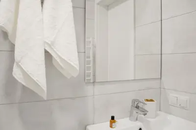 a white bathroom with a sink and a mirror at Tip Tap Guest House in Druskininkai