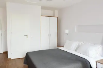 a bedroom with a large bed with white cabinets at Tip Tap Guest House in Druskininkai