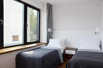 two beds in a room with two windows at Tip Tap Guest House in Druskininkai