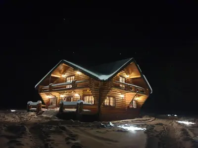 a log cabin in the snow at night at Poilsio ir sveikatinimo sodyba Pušų Šlamesy in Vilnius