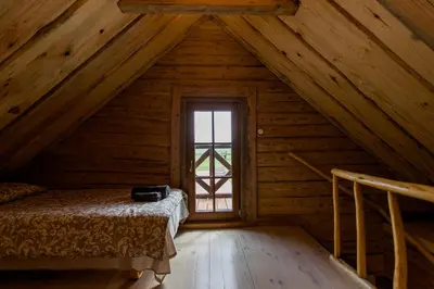 an attic room with a bed and a window at ETNO house in Ricieliai