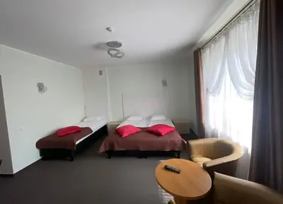 a bedroom with two beds with red pillows and a chair at La-Vanda in Šiauliai