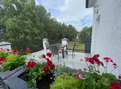 a patio with red flowers and a table and chairs at La-Vanda in Šiauliai