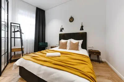 a bedroom with a large bed with a yellow blanket at Modern apartment in Kaunas city center in Kaunas