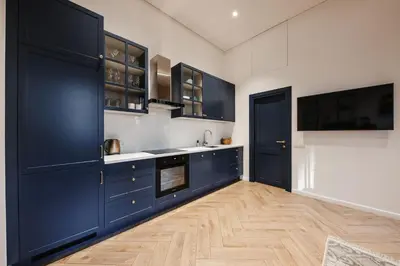 a kitchen with blue cabinets and a wooden floor at Modern apartment in Kaunas city center in Kaunas