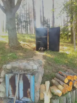 a fire pit in a field next to a tree at Kaimo turizmo sodyba Stromelė in Baltriškės