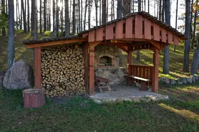 a small cabin with a bench in the woods at Kaimo turizmo sodyba Stromelė in Baltriškės