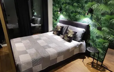 a bedroom with a bed with a green wall at Ozas Green Apartment in Vilnius