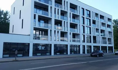 a white building with a car parked in front of it at Ozas Green Apartment in Vilnius