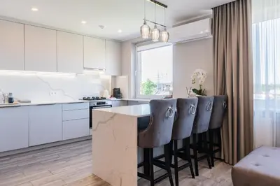 a kitchen with white cabinets and a island with bar stools at E.D. Luxury Apartaments in Šiauliai