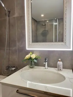 a bathroom sink with a mirror and a vase of flowers at E.D. Luxury Apartaments in Šiauliai