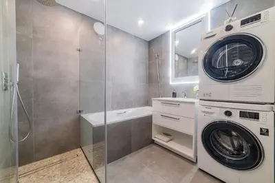 a bathroom with a washer and dryer next to a shower at E.D. Luxury Apartaments in Šiauliai