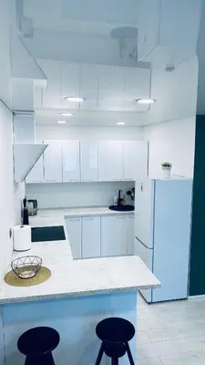 a kitchen with white cabinets and two stools at Green & White Apartament in Anykščiai