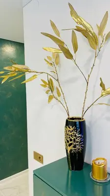 a black vase with a plant in it on a table at Green & White Apartament in Anykščiai