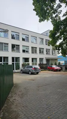 two cars parked in a parking lot in front of a building at Skuodo 2E in Kaunas