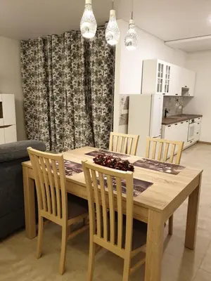 a wooden dining room table with chairs and a kitchen at Skuodo 2E in Kaunas