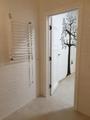 a bathroom with a door with a tree stencil on the wall at Skuodo 2E in Kaunas