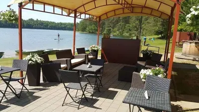 a group of tables and chairs under a pavilion next to a lake at ORO Dubingiai in Giraičiai