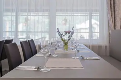 a table with wine glasses and a vase of flowers at ORO Dubingiai in Giraičiai