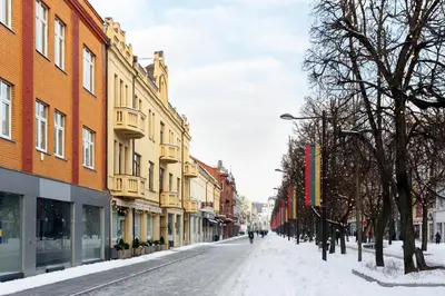 a snow covered street in a city with buildings at Laisves ave. Apartments Mini in Kaunas