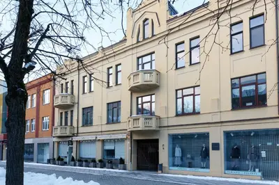 a large building on a street with a tree at Laisves ave. Apartments Mini in Kaunas