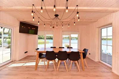 a dining room with a wooden table and chairs at Namelis ant vandens 