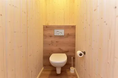 a bathroom with a toilet in a wooden wall at Namelis ant vandens 
