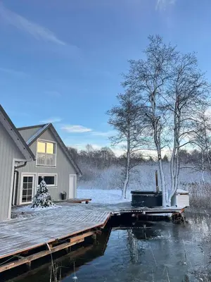 a house with a wooden dock in the water at Namelis ant vandens 