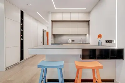 a kitchen with white cabinets and two blue stools at HaPPy Inn G, Self check-in, Terrace, Underground Parking in Vilnius