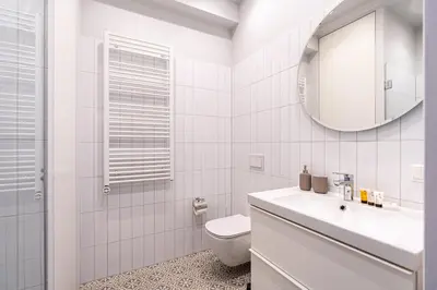 a white bathroom with a toilet and a mirror at Cozy Apartment In Kaunas Center in Kaunas