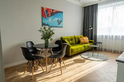 a living room with a green couch and a table and chairs at Wonderful Apartment In The Heart Of Kaunas Center in Kaunas