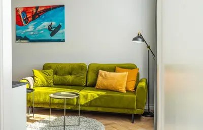 a green couch with yellow pillows in a living room at Wonderful Apartment In The Heart Of Kaunas Center in Kaunas