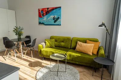 a living room with a green couch and two tables at Wonderful Apartment In The Heart Of Kaunas Center in Kaunas