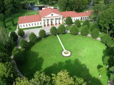 a large building with a large clock on a lawn at Taujėnų dvaro svečių namai in Towiany
