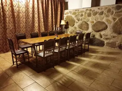a wooden table with chairs and a stone wall at Taujėnų dvaro svečių namai in Towiany