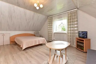 a bedroom with a bed and a tv and a table at Augutės Zurlienės apartamentai in Trakai