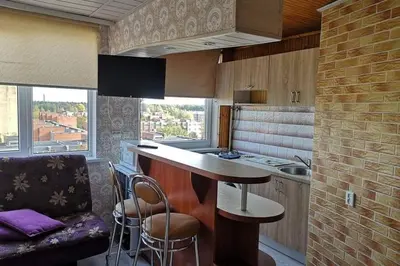 a kitchen with a counter and a bar with stools at Pigūs apartamentai Panevėžyje in Panevėžys