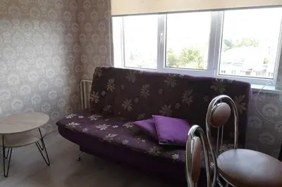 a living room with a purple couch and a table at Pigūs apartamentai Panevėžyje in Panevėžys