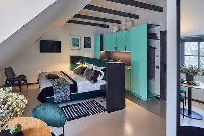 a bedroom with a bed with a green headboard at ROOMA Apartments Boutique Old Town Self Check-in in Vilnius