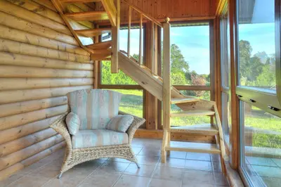 a room with a chair and a staircase in a cabin at Bilso Sodyba in Vilkanastrai