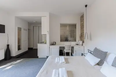 a white room with a table and a kitchen at Moon Garden Old Town Hotel in Vilnius