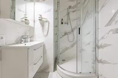 a white bathroom with a shower and a sink at St Casimir Apartments in Vilnius