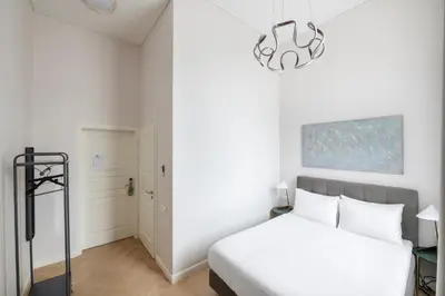 a bedroom with a white bed and a chandelier at St Casimir Apartments in Vilnius