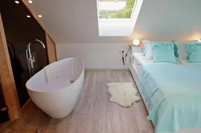 a bathroom with a bath tub next to a bed at Lavender Village in Kiemeliai