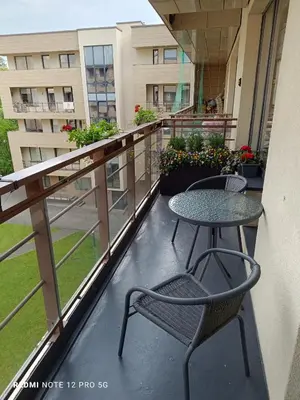 a balcony with two tables and chairs on a building at Nelli apartamentai in Druskininkai