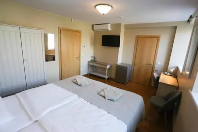 a bedroom with a large white bed and a chair at Hotel Jonapolis in Jonava