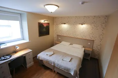 a bedroom with a bed and a desk and a window at Hotel Jonapolis in Jonava