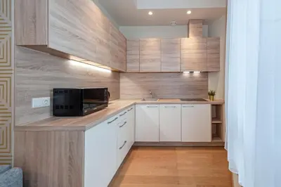 a small kitchen with white cabinets and a microwave at Eva R Apartments in Druskininkai
