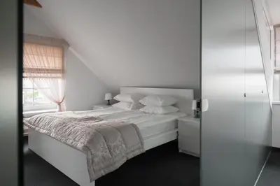 a white bedroom with a bed and a window at Laurentroom Oldtown in Ukmergė